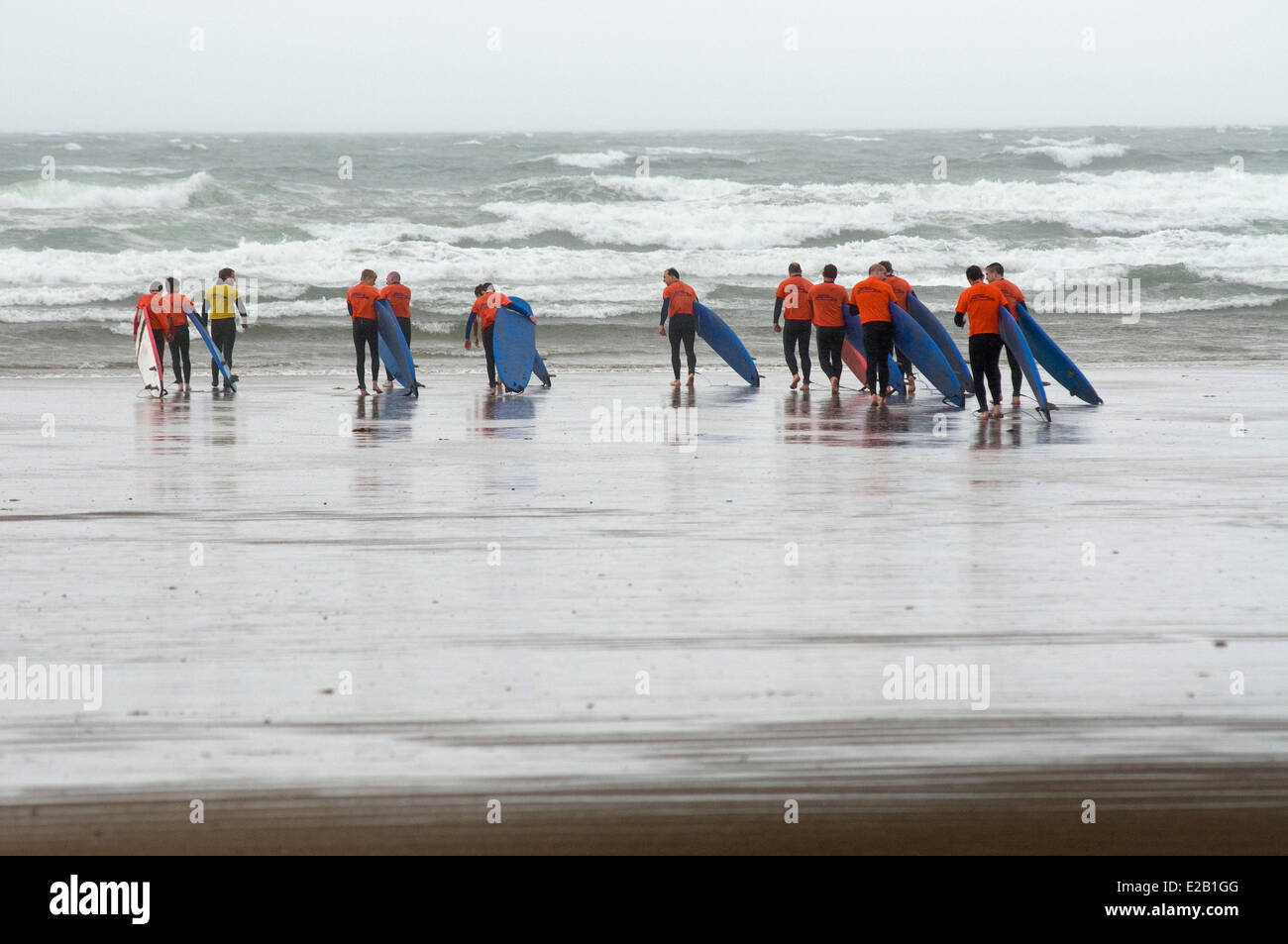 Ireland, County Kerry, Inch, surfers walking on the beach in bad weather Stock Photo