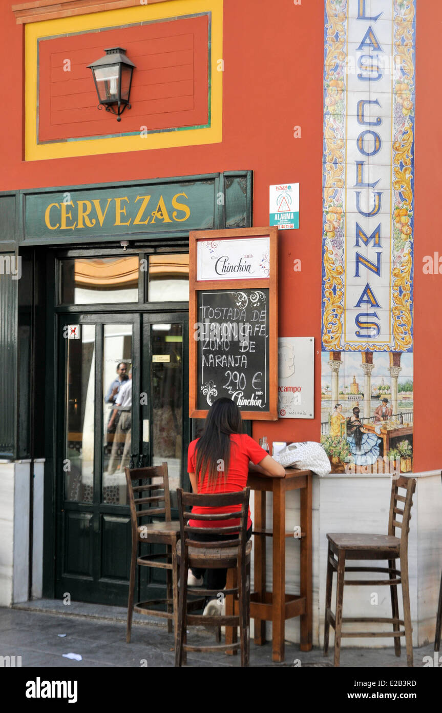 Spain, Andalucia, Seville, Triana, Las Columnas bar, table and chairs in the street, a single woman Stock Photo