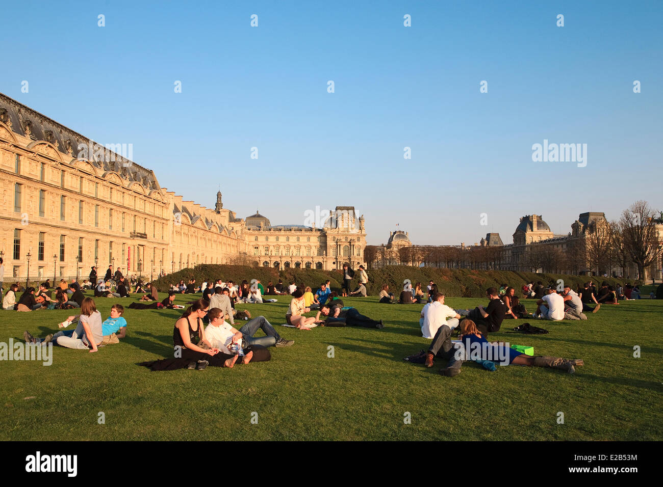 France, Paris, people sunbathing in the Jardins du Carrousel and the Louvre museum in the background Stock Photo