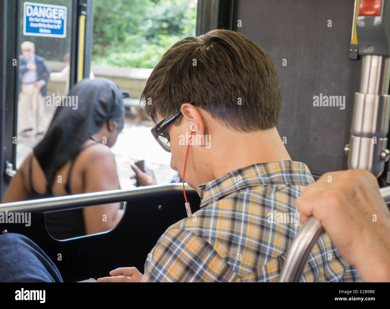 A bus rider wears his Beats by Dr. Dre earbud while riding on Friday, June 13, 2014 (© Richard B. Levine) Stock Photo