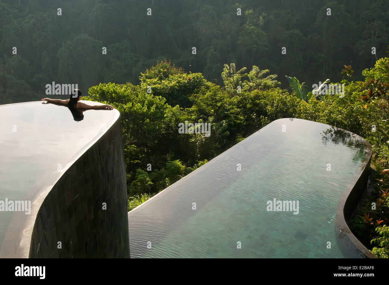 Indonesia, Bali, Gianyar, Buahan Payangan, Ubud Hanging Gardens hotel group Orient-Express, one young woman back outstretched arms, infinity pool overlooking the jungle at sunrise Stock Photo