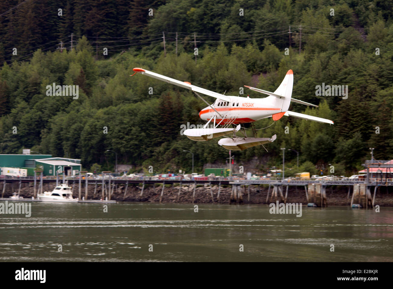Float Plane flying through the mountains over docks  Juneau Alaska Stock Photo