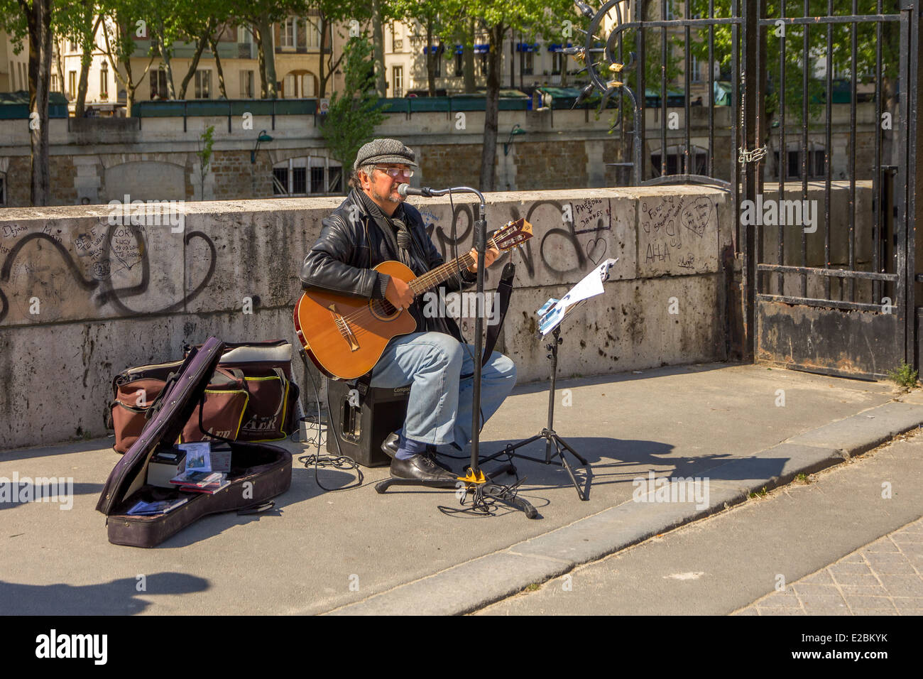PARIS - MAY 3: Busker sings French chanson with a guitar on the waterfront near Notre Dame in Paris on 3 may 2014. Stock Photo