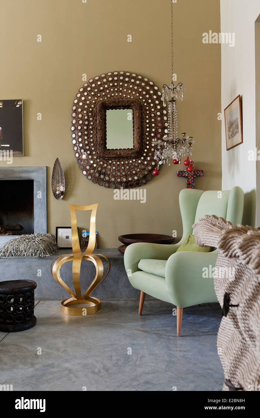 Jewelled mirror with pastel green armchair in Baja home with polished cement floor Stock Photo