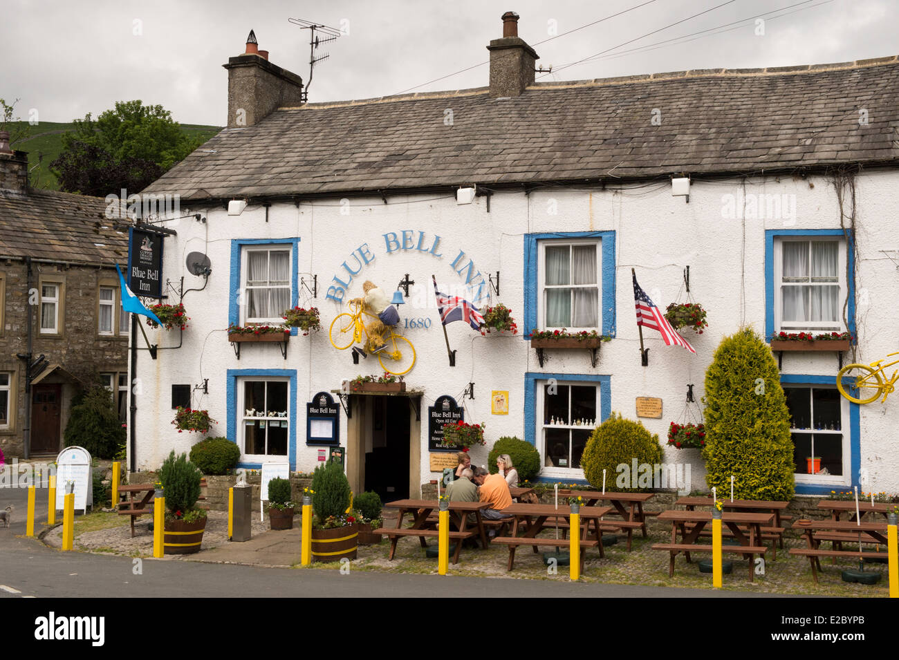 People sit at tables, eat & drink outside attractive, traditional English pub - The Blue Bell Inn, Kettlewell village, Yorkshire Dales, England, UK. Stock Photo