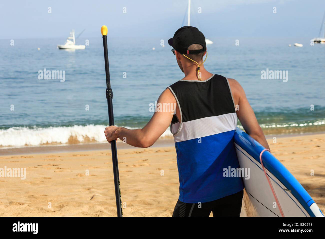 Man with stand up paddle board walks to ocean at Kaanapali Beach on Maui Stock Photo