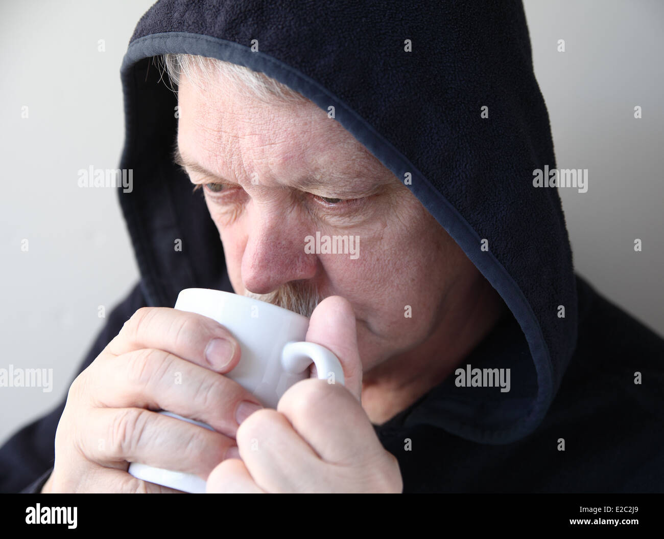 senior in black jacket with hands around a coffee cup Stock Photo