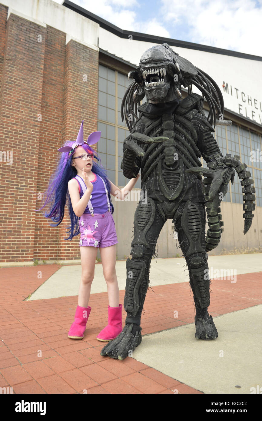 Garden City, New York, USA. 14th June, 2014. A young girl in a Twilight Sparkle costume from My Little Pony pretends to be scared of her father in an Alien costume, based on Alien VS Predator movie, in front of an historic Mitchel Field hangar at Eternal Con, the Long Island Comic Con Pop Culture Expo, held at the Cradle of Aviation Museum. © Ann Parry/ZUMA Wire/ZUMAPRESS.com/Alamy Live News Stock Photo