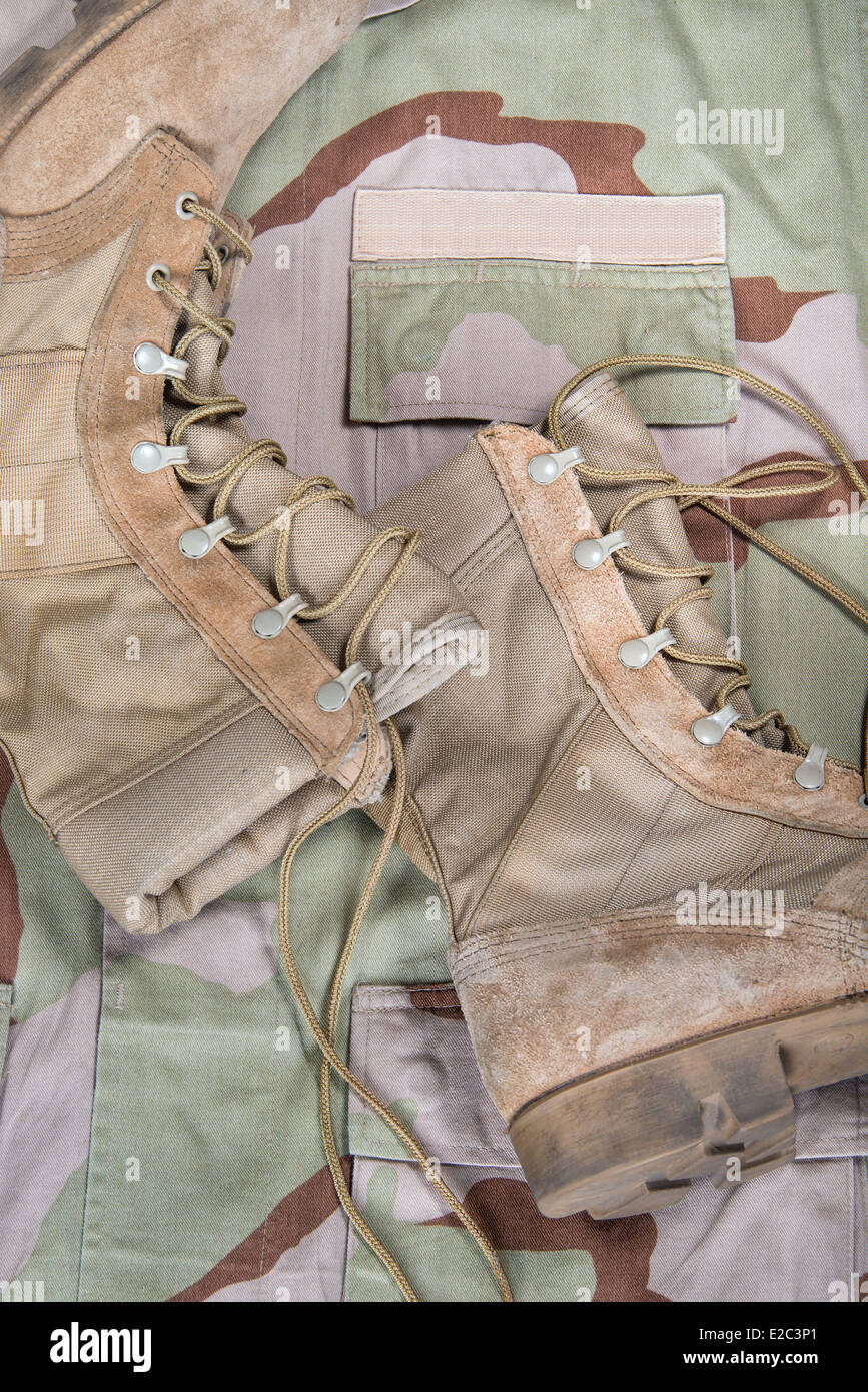 Old combat boots against camouflage desert uniform Stock Photo