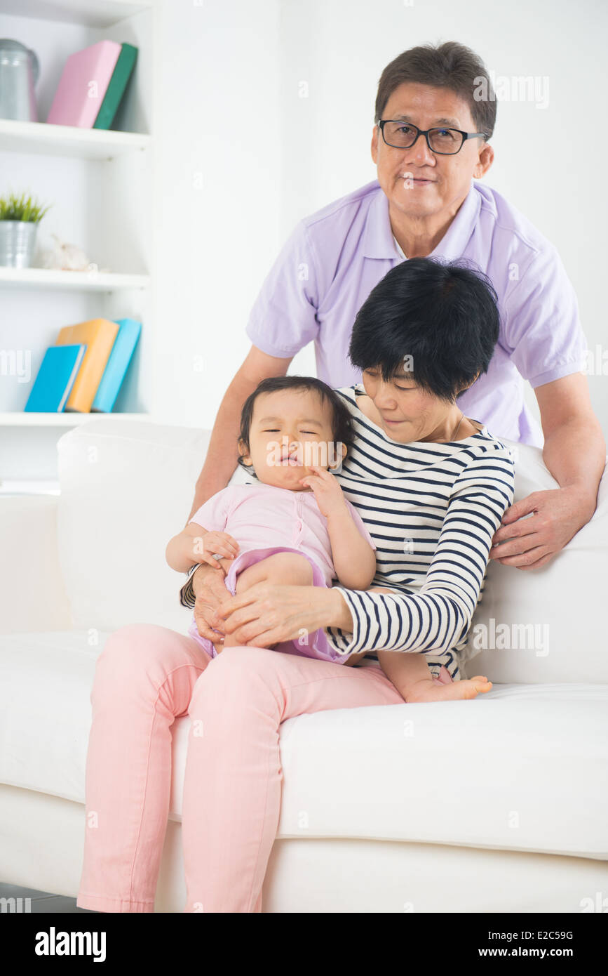 asian grand parents comforting their spoilt crying grand daugther Stock Photo