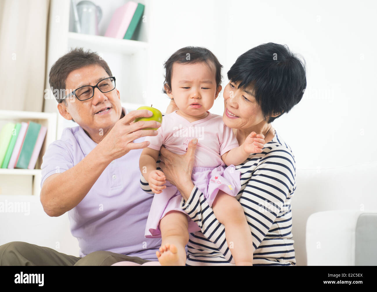 asian grand parents comforting their spoilt crying grand daugther Stock Photo