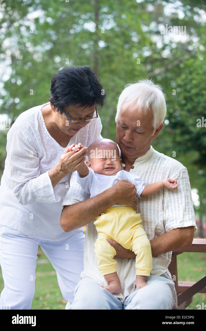 asian grandparents comforting crying baby grandson at outdoor Stock Photo