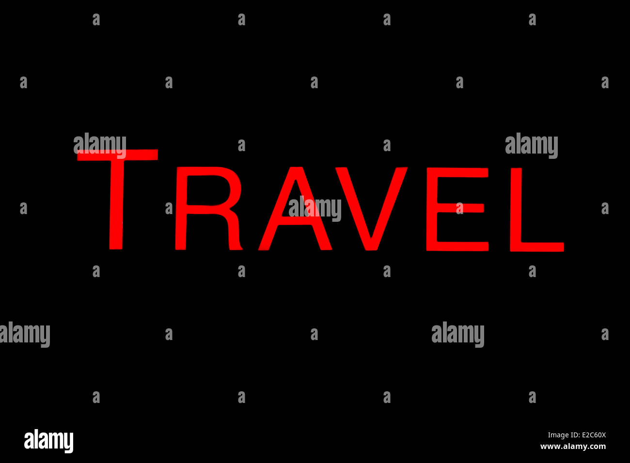 Illuminated red travel sign against a black background. Stock Photo