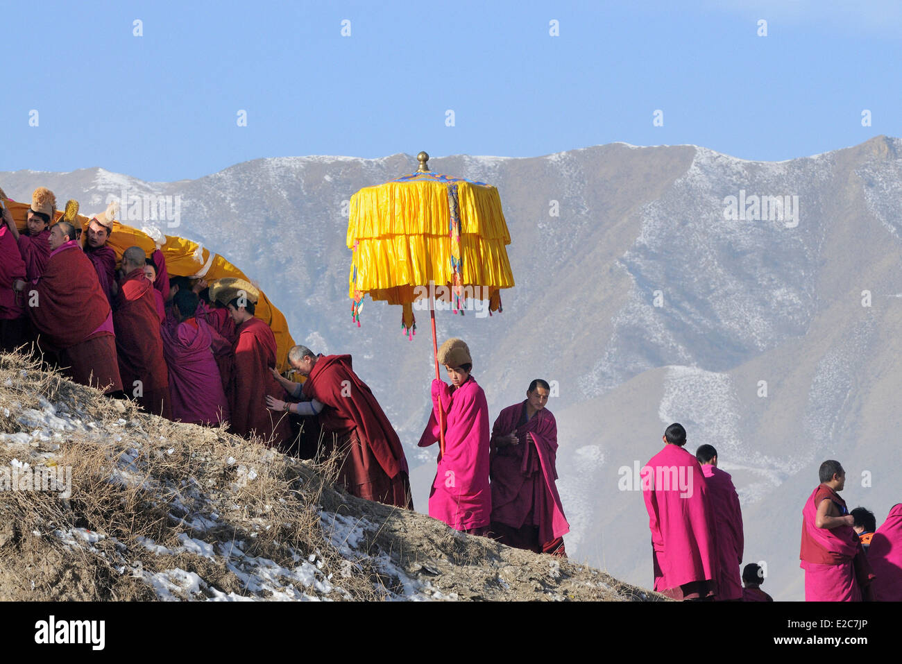 China, Gansu Province, Amdo, Xiahe, Monastery of Labrang, Losar, Giant Thangka and parasol bearers climbing uphill Stock Photo