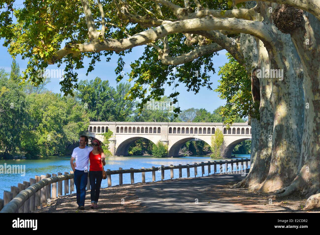 France, Herault, Beziers, Path of New Port, couple in walk at edge of river Orb with Bridge Canal in background Stock Photo