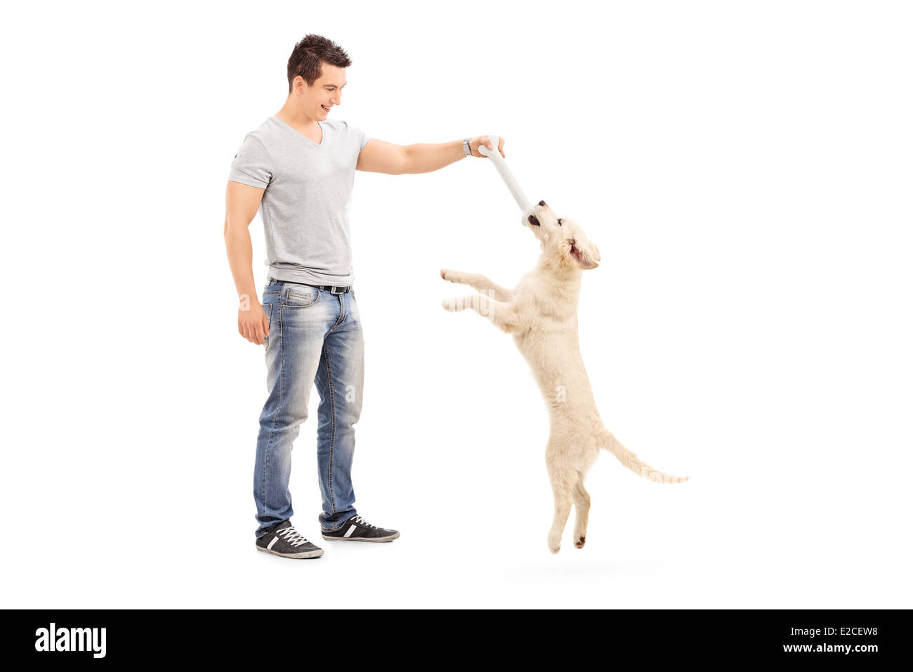 Full length portrait of a young man holding a bone and playing with a puppy Stock Photo