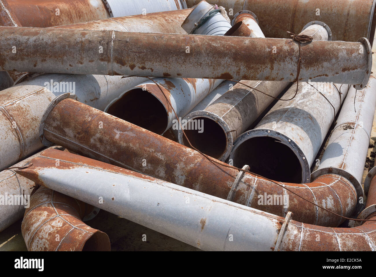 A stack of rusty and damaged industrial pipes and other metal products