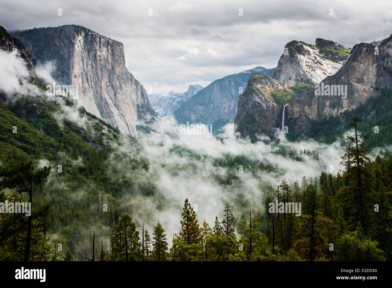 Yosemite Valley with Half Dome on the left with waterfall and fog in Yosemite National Park. Stock Photo