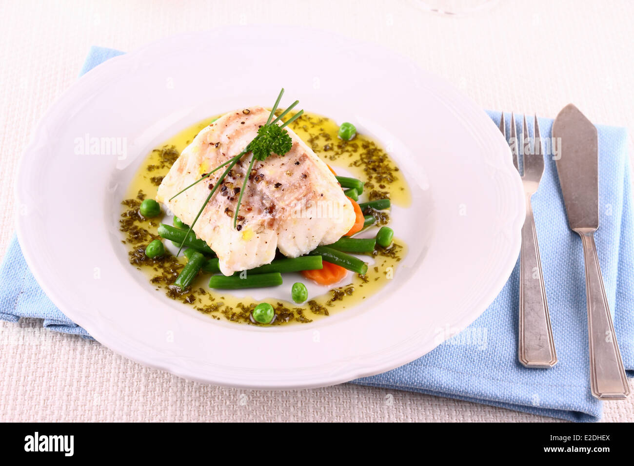 Cod fillet with green beans, peas, parsley, olive oil, close up Stock Photo
