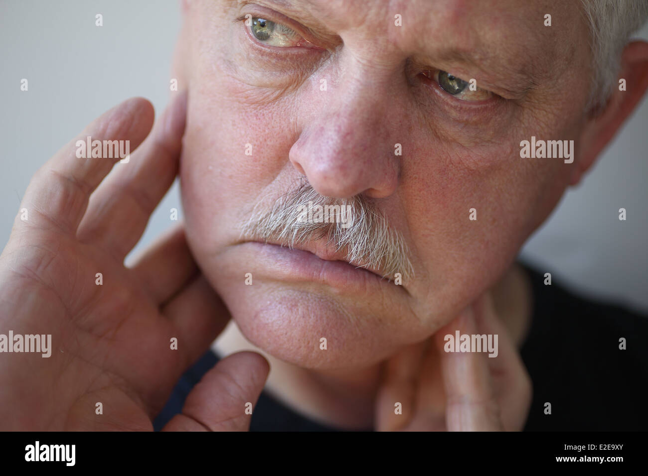 senior man touches his sore jaw area Stock Photo
