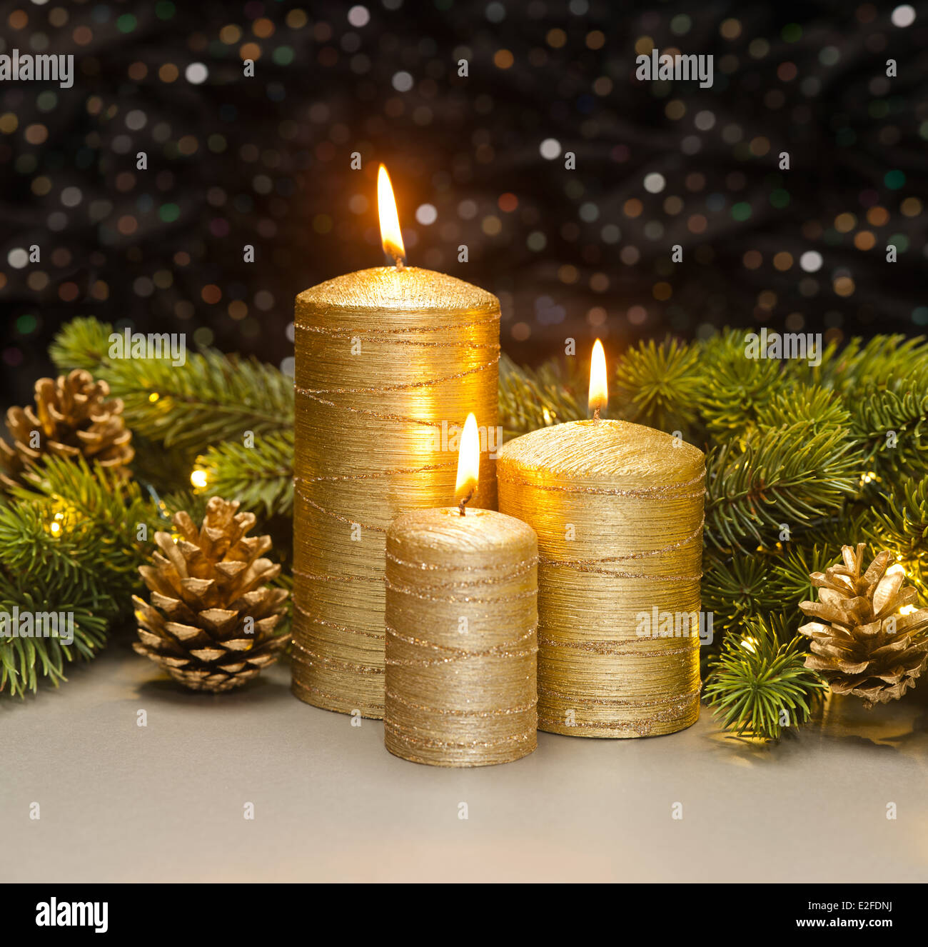 Three golden Candles with Christmas tree branches and pine cones ...