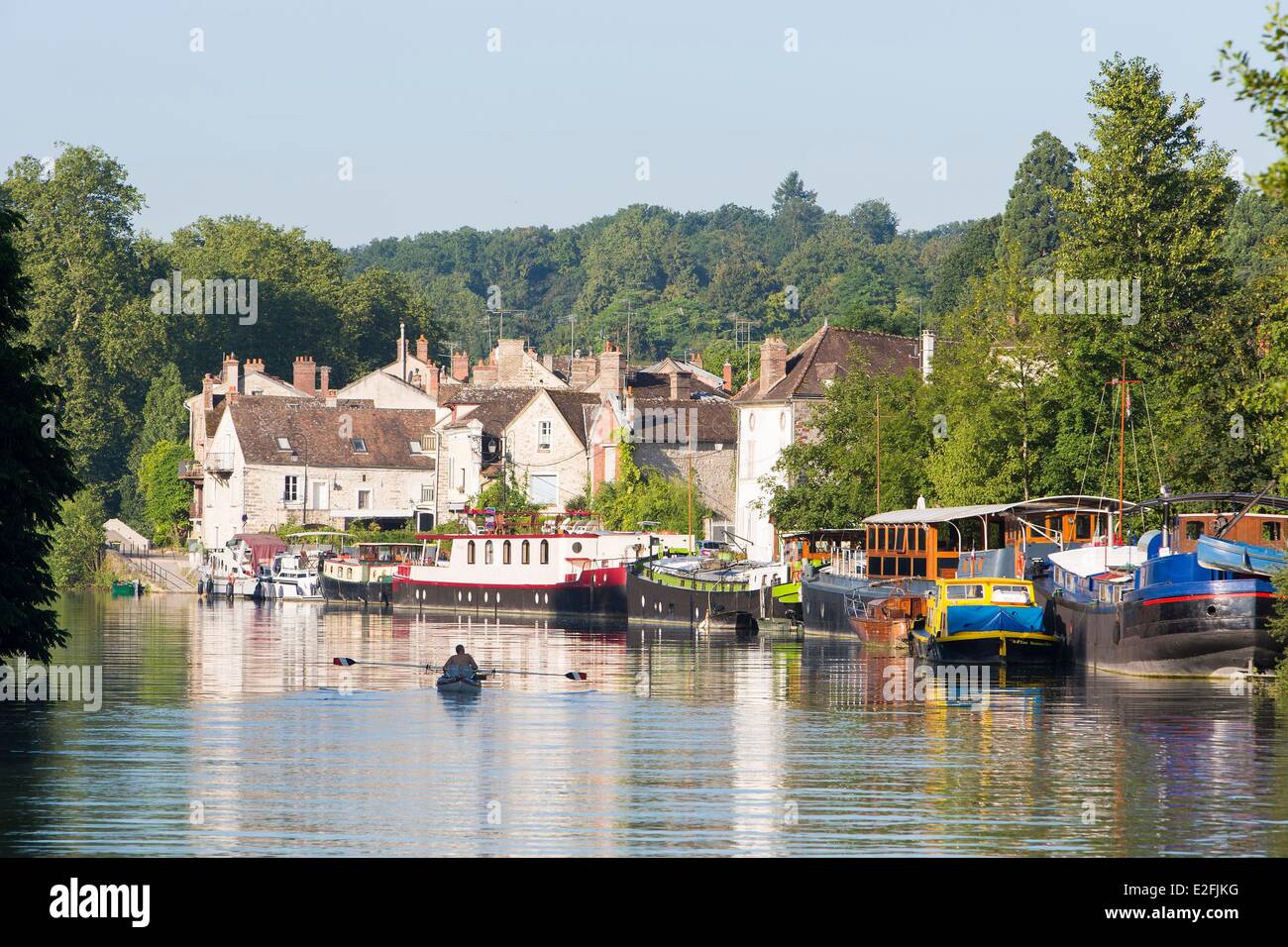 France Seine et Marne Samois sur Seine man rowing flat boats moored at wharf on the Seine river and village in the background Stock Photo