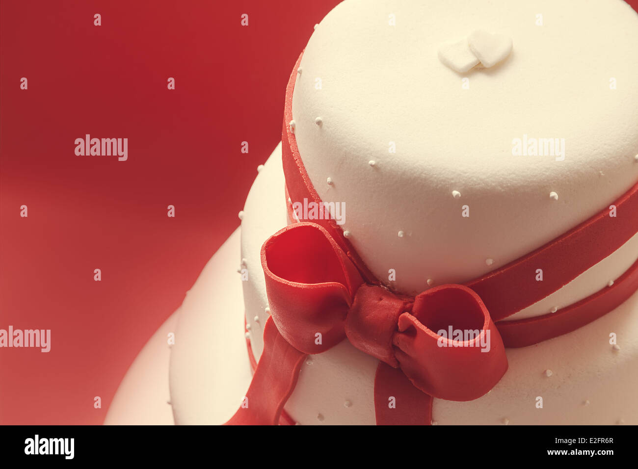 Details of wedding cake, decorated with red sugar ribbons. Stock Photo