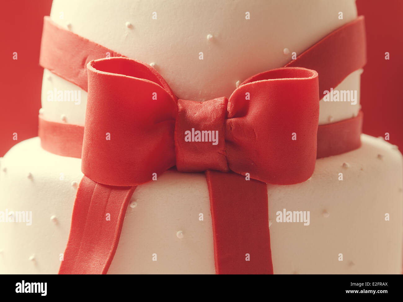 Details of wedding cake, decorated with red sugar ribbons. Stock Photo