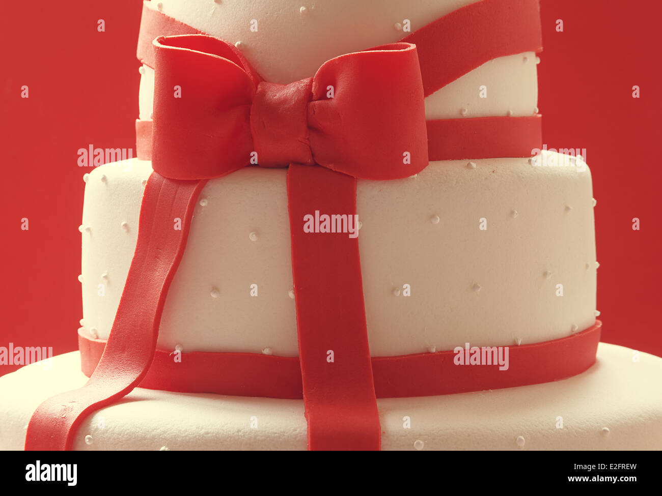 Details of wedding cake, decorated with red sugar ribbons. Stock Photo