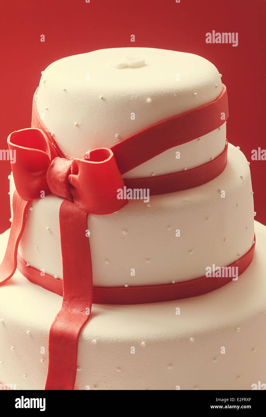 Details of wedding cake, decorated with red sugar ribbons. Stock Photo