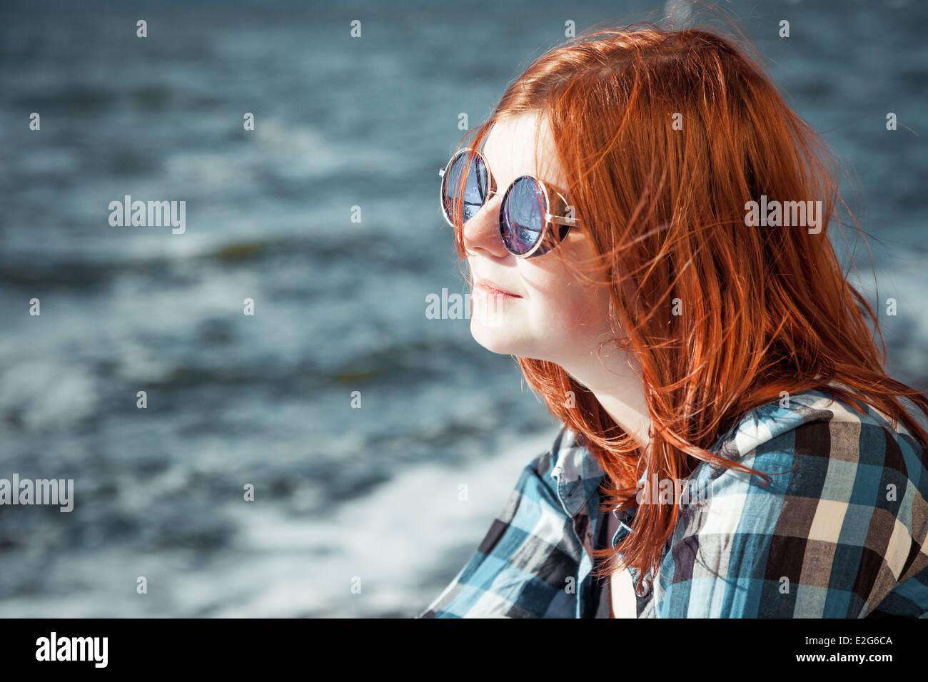 carefree beautiful red hair young woman in sunglasses over seascape Stock Photo