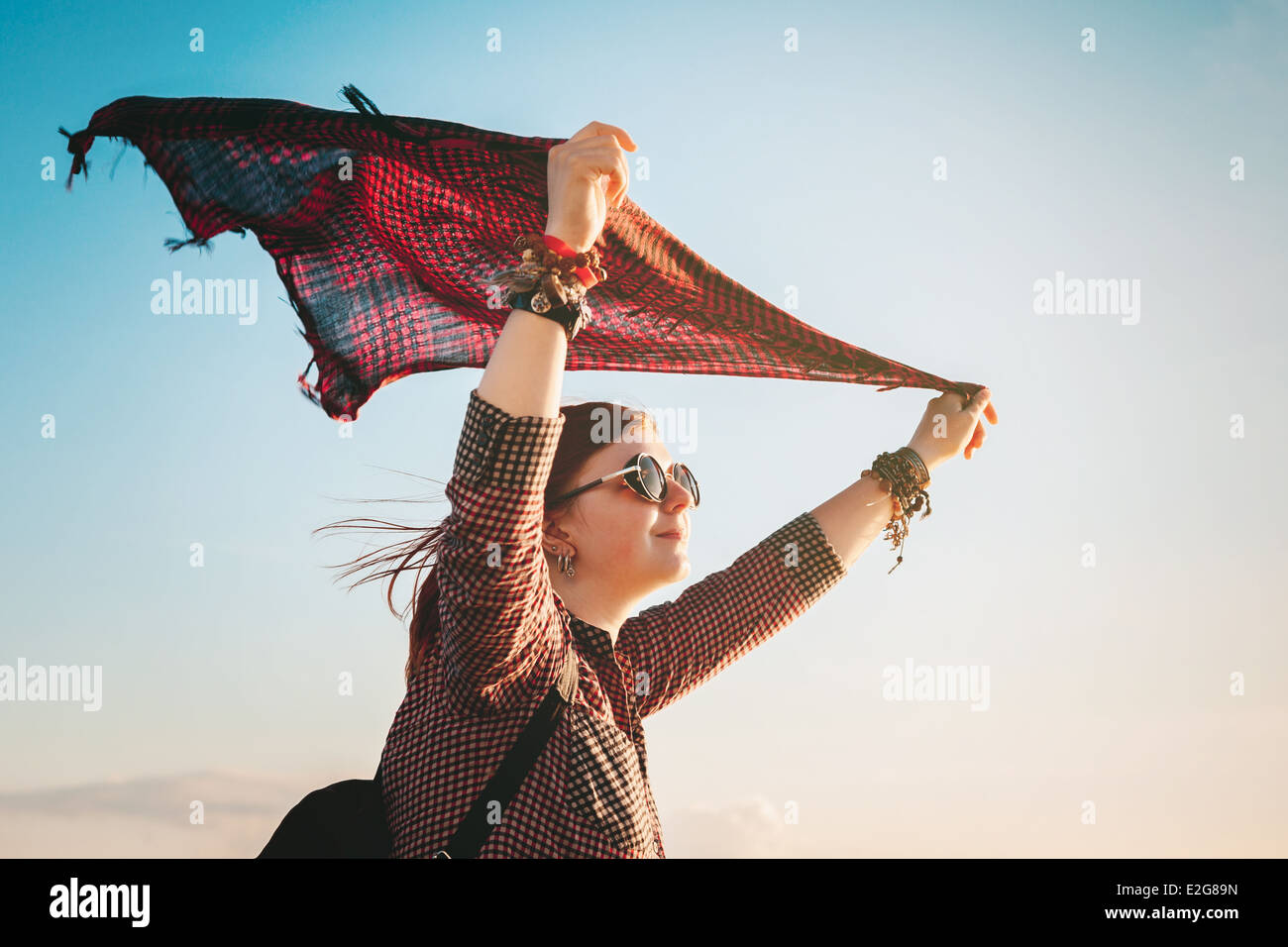 romantic young woman with red fluttering scarf in sunset light Stock Photo
