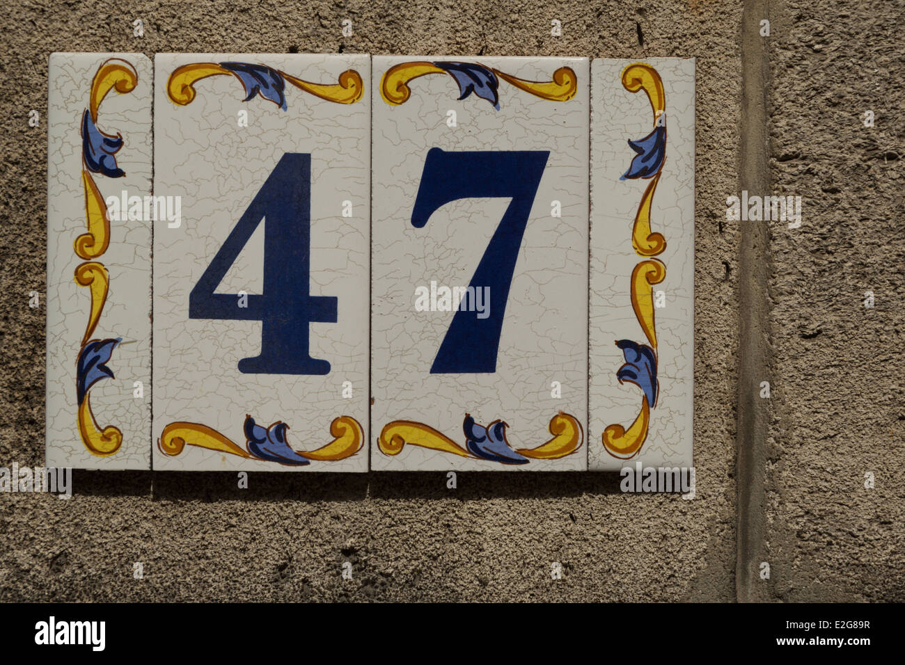 A photograph of a house number 47, made from colorful old ceramic tiles. Stock Photo