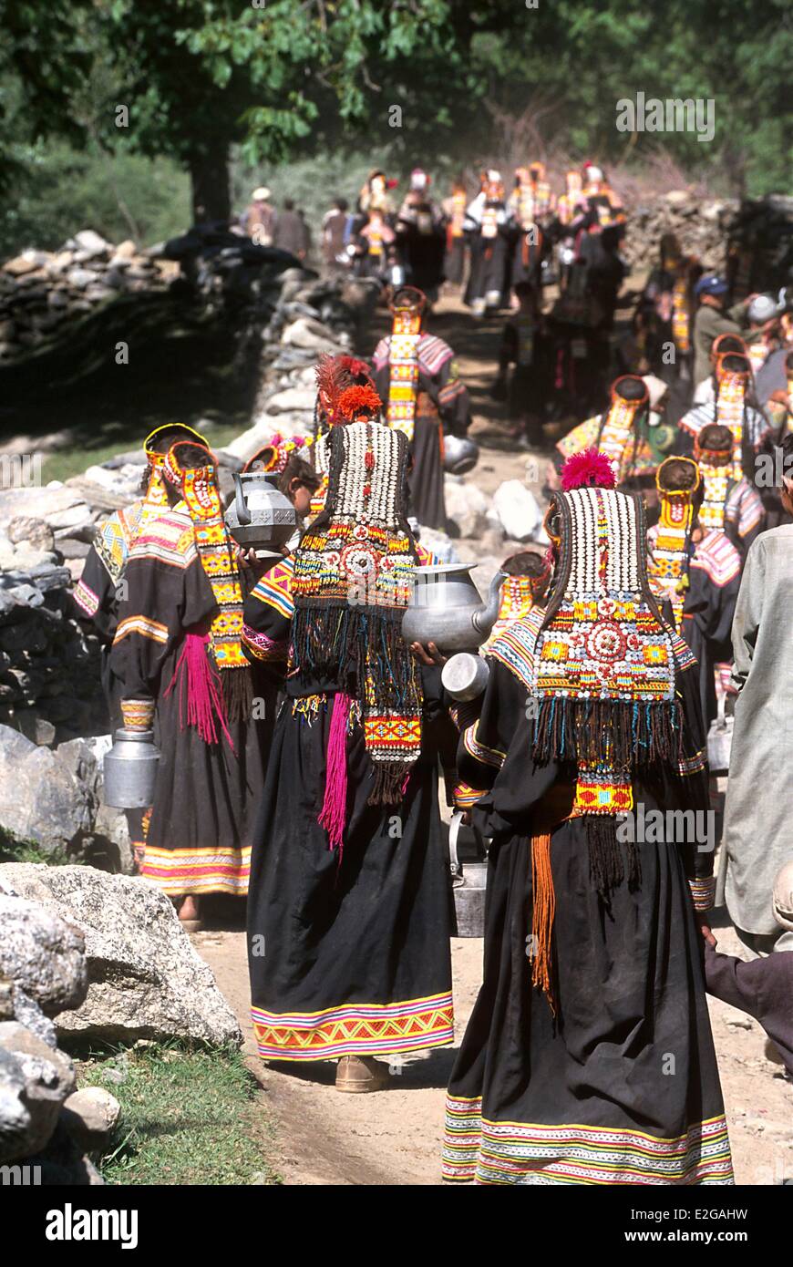 Pakistan Khyber Pakhtunkhwa Kalash valleys Bumburet valley Krakal village in procession and with receptacles women and children Stock Photo