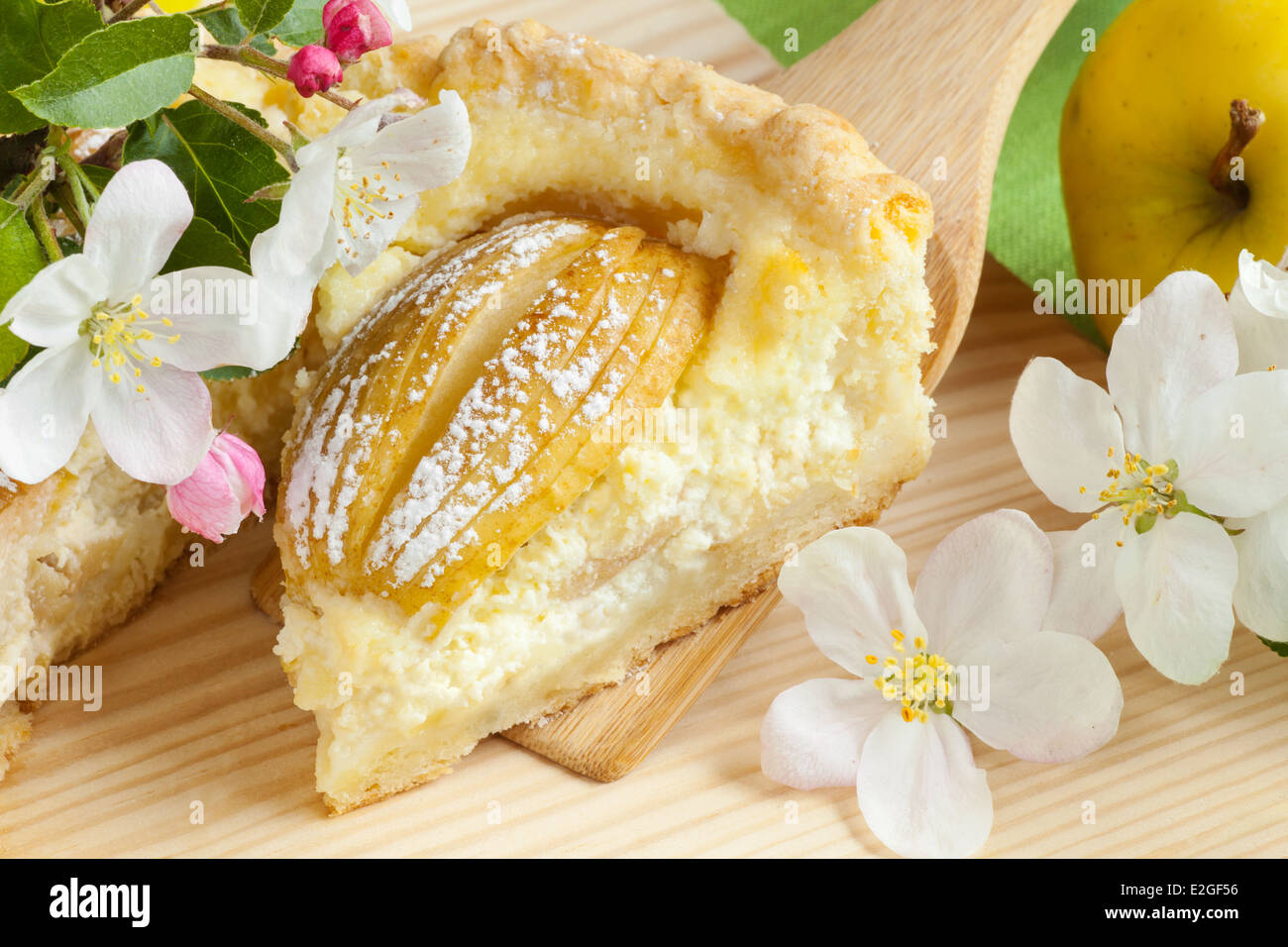 piece of homemade apple cake, apple fruit and blossom tree branch on kitchen table Stock Photo