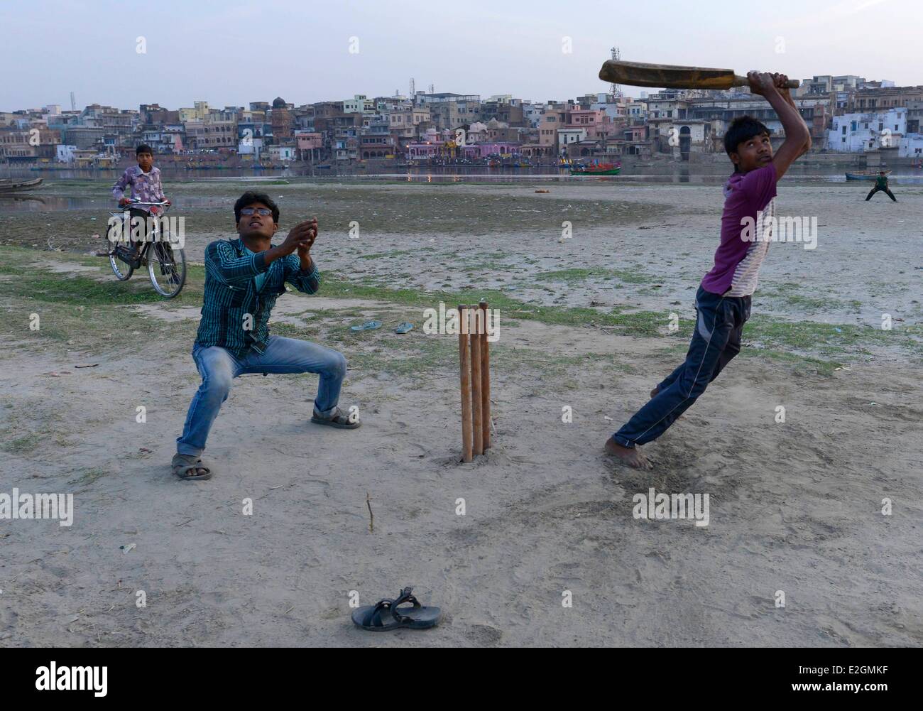 India Uttar Pradesh State Mathura children play cricket along river during Holi festival celebrations Stock Photo