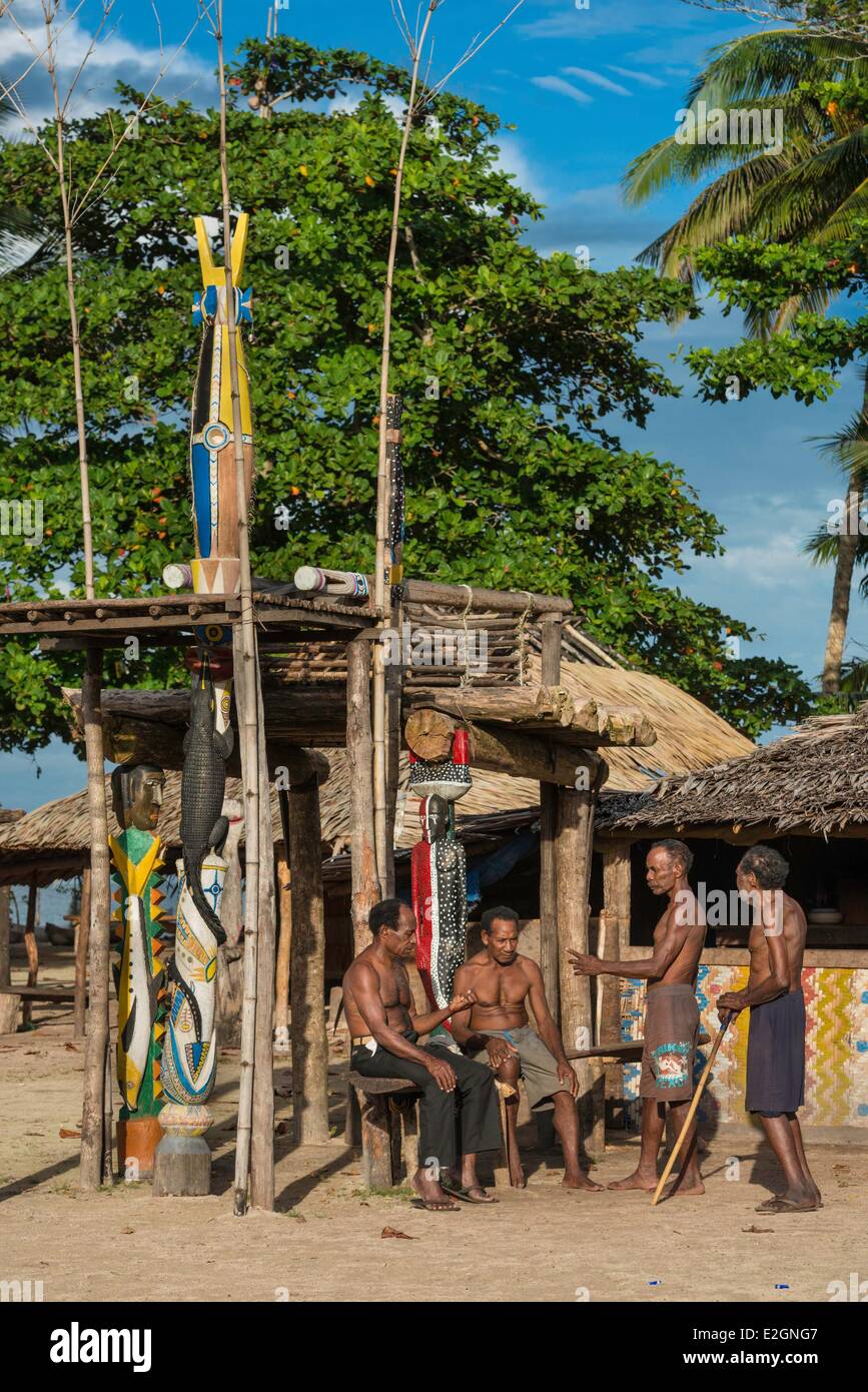 Papua New Guinea New Britain island West New Britain province Talasea district Kimbe area Kapo island men in front of houseman with traditional carving related to initiation ceremonies Stock Photo