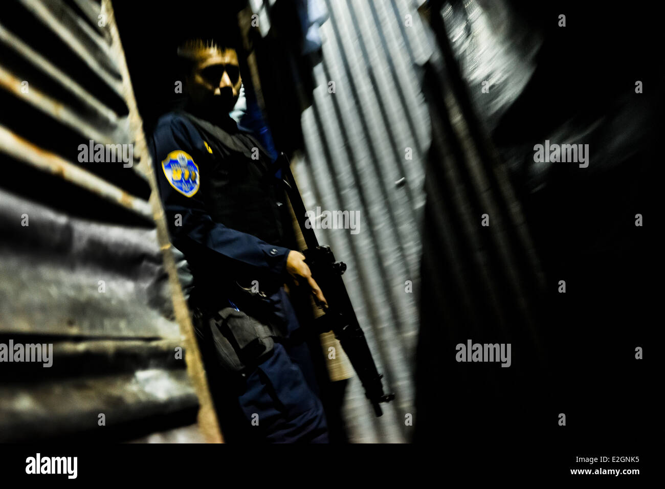 A policeman from the special emergency unit chases supposed gang members during the night in San Salvador, El Salvador. Stock Photo