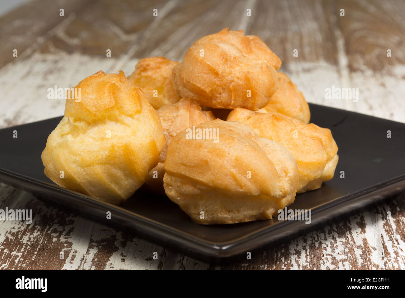 eclair on black ceramic plate on wood background Stock Photo