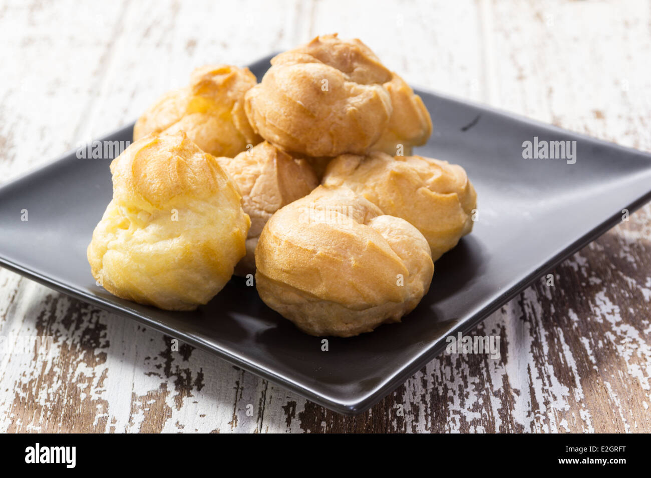 eclair on black ceramic plate on wood background Stock Photo
