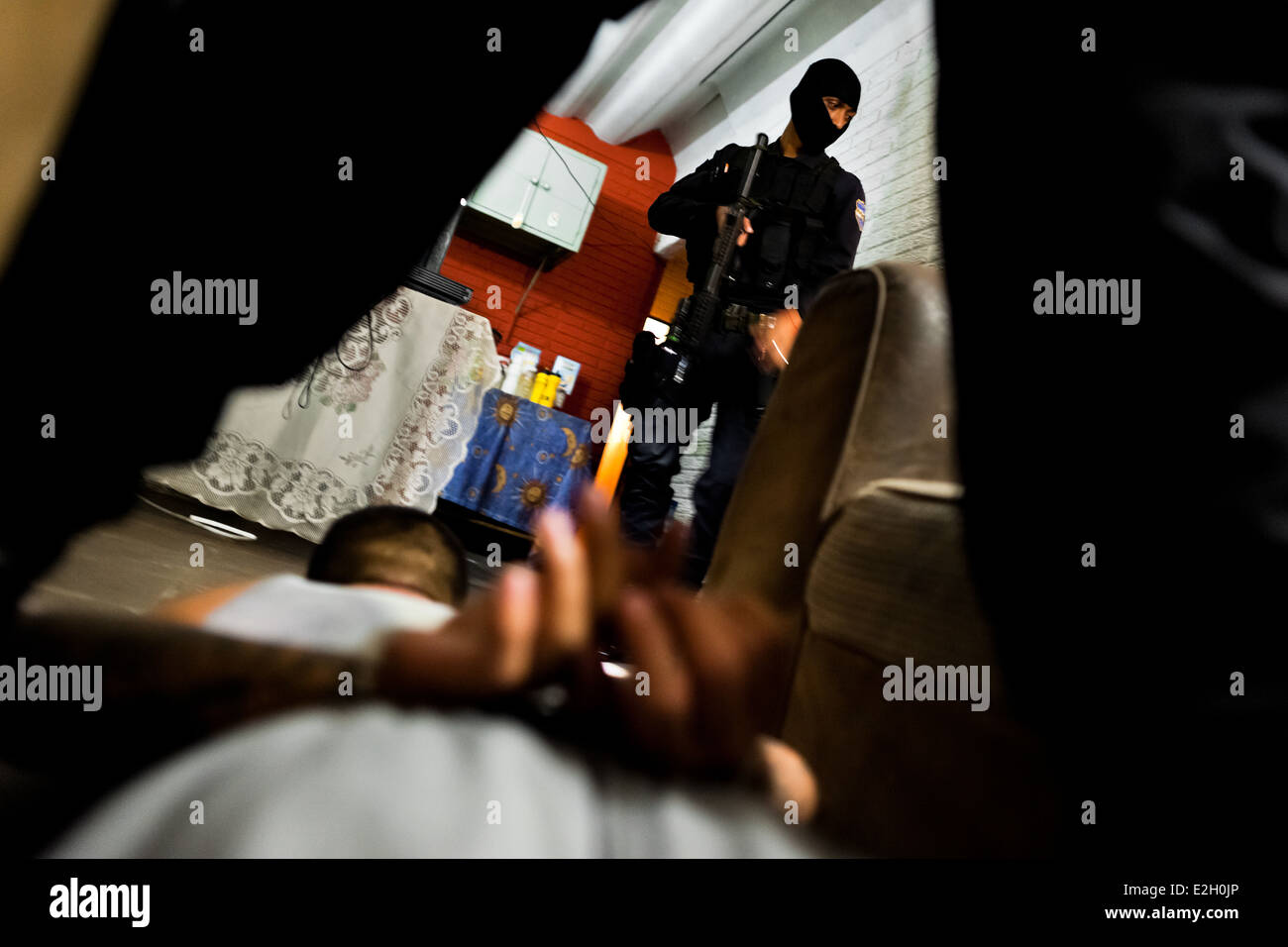 A policeman from the special anti-gang unit searches an apartment during a night raid in San Salvador, El Salvador. Stock Photo