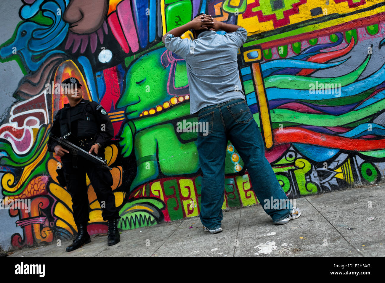 An alleged gang member is controlled by a policeman from the special emergency unit on the street in San Salvador, El Salvador. Stock Photo