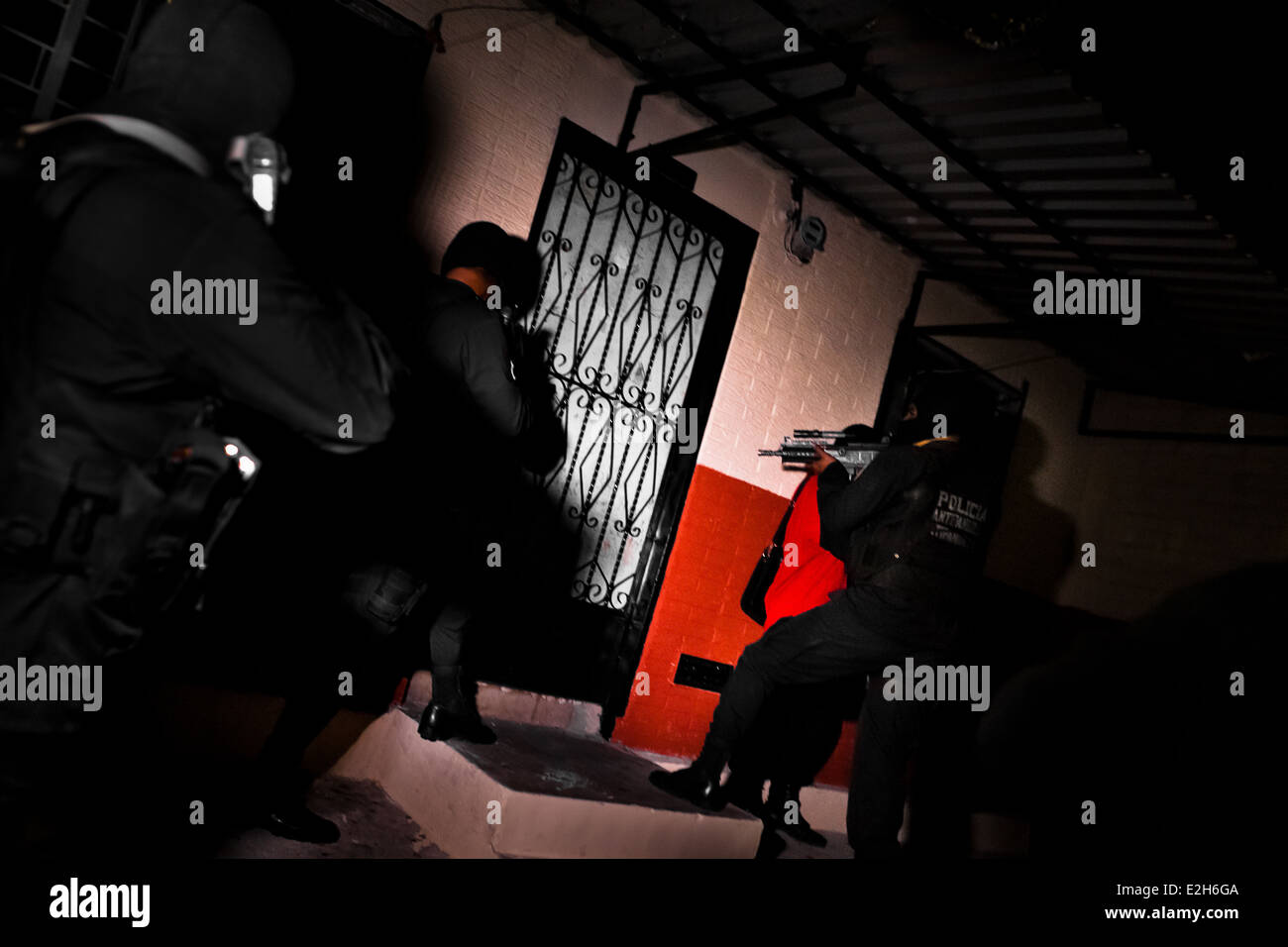 Policemen from the special anti-gang unit enter the apartment of an alleged gang member in San Salvador, El Salvador. Stock Photo