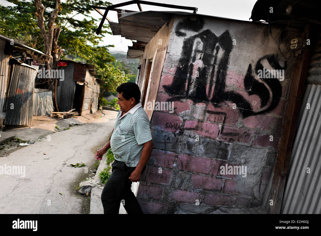 A Salvadoran man passes in front of the Mara Salvatrucha graffiti in a gang neighborhood in San Salvador, El Salvador. Stock Photo