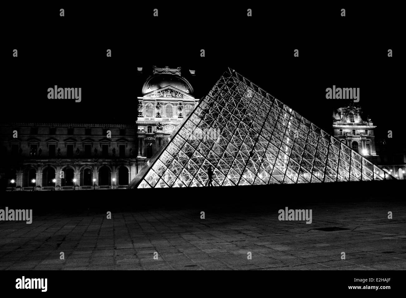The Louvre Pyramid, a large glass and metal pyramid structure in the centre of the Louvre art gallery, Paris. Lit up at night. Stock Photo