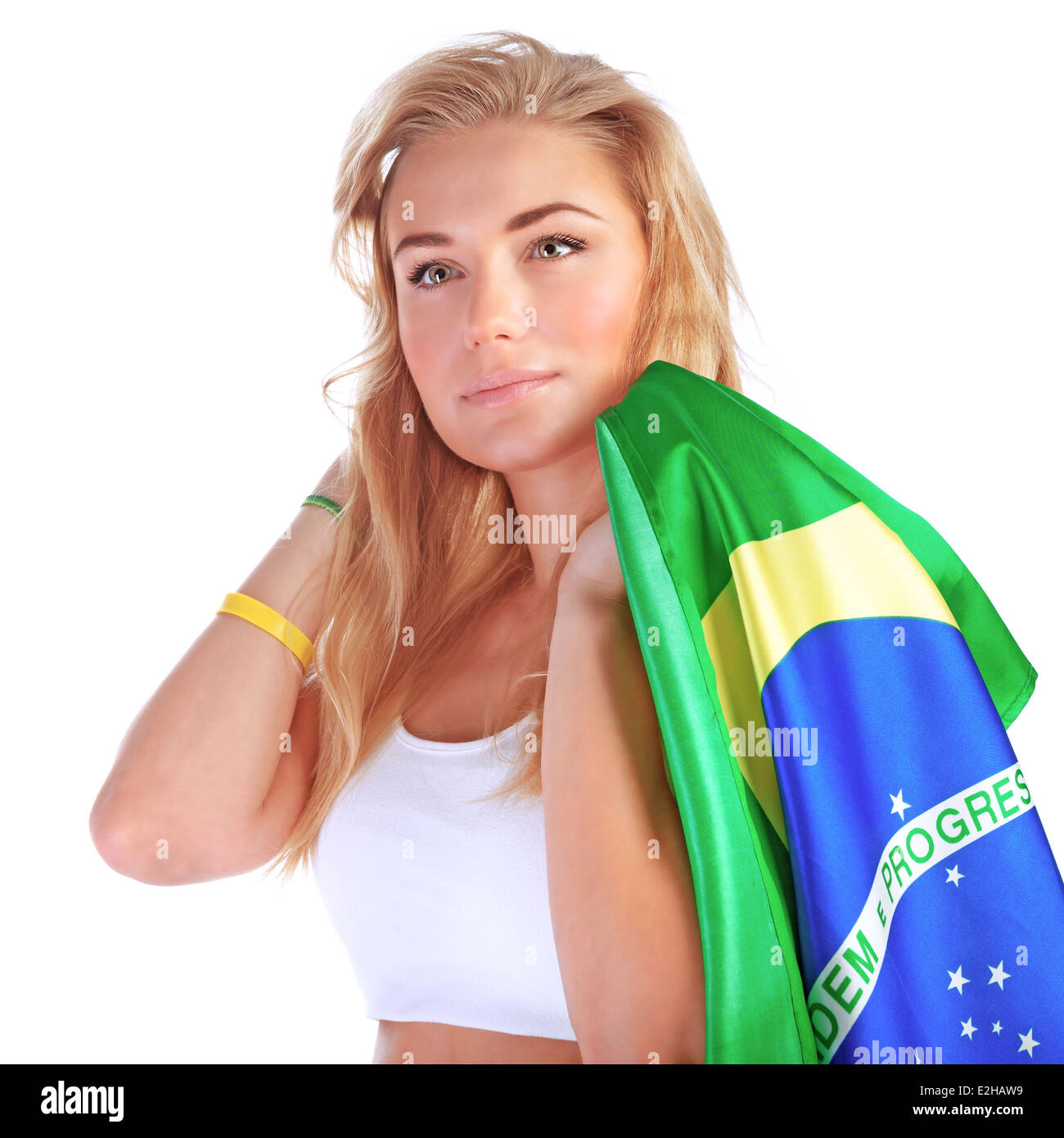 Portrait of cute blond girl holding in hand Brazil national flag isolated on white background, serious fan of Brazilian football Stock Photo