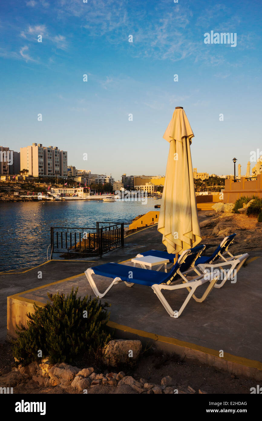 Two sunbeds and parasol, overlooking St Bay, Malta Stock Photo