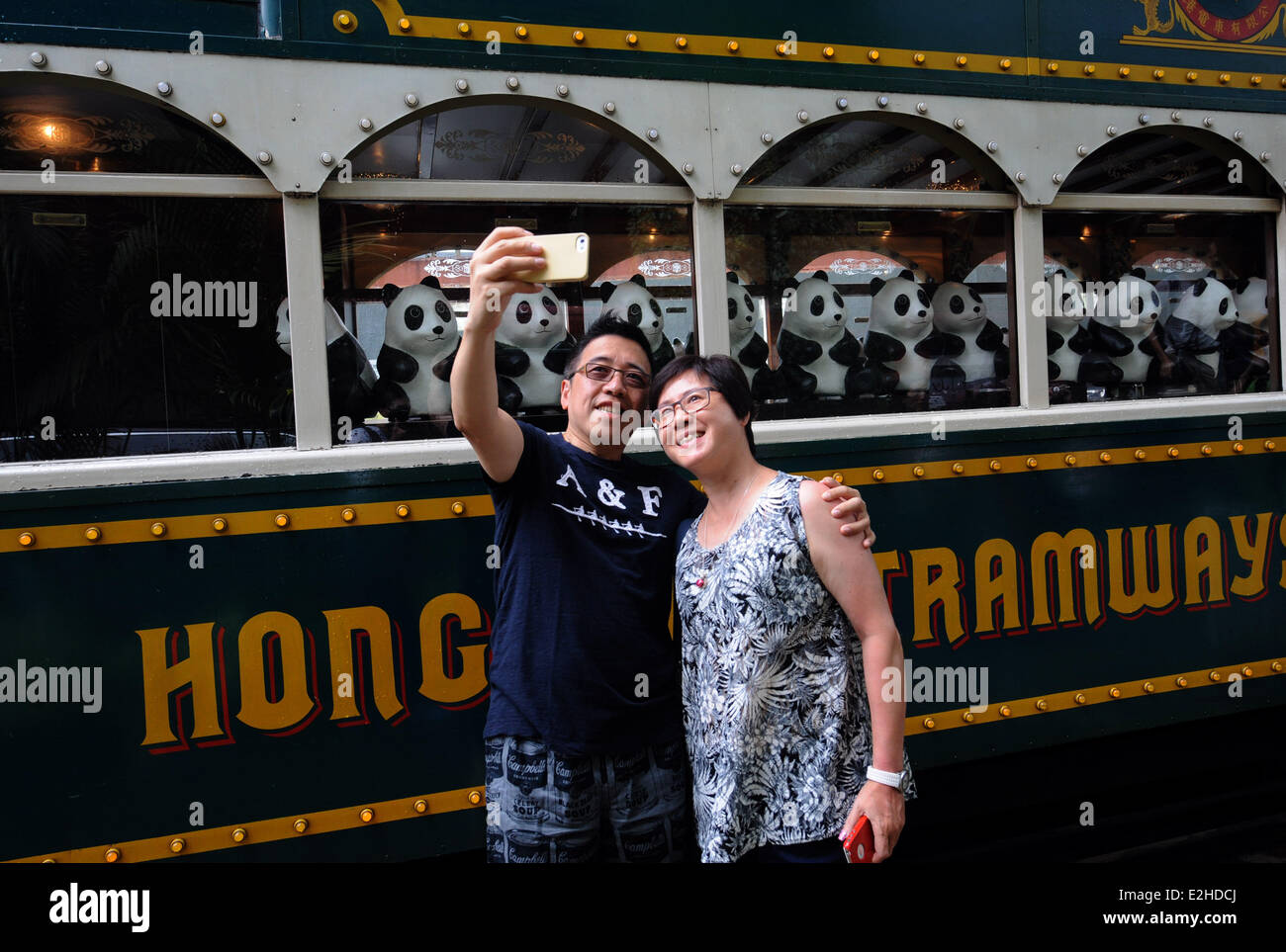 Hong Kong, China. 20th June, 2014. Residents pose for photos with paper pandas which travel on a tram in Hong Kong, south China, June 20, 2014. A total of 1,600 paper pandas, the work of French artist Paulo Grangeon, were displayed in Hong Kong. © Lo Ping Fai/Xinhua/Alamy Live News Stock Photo