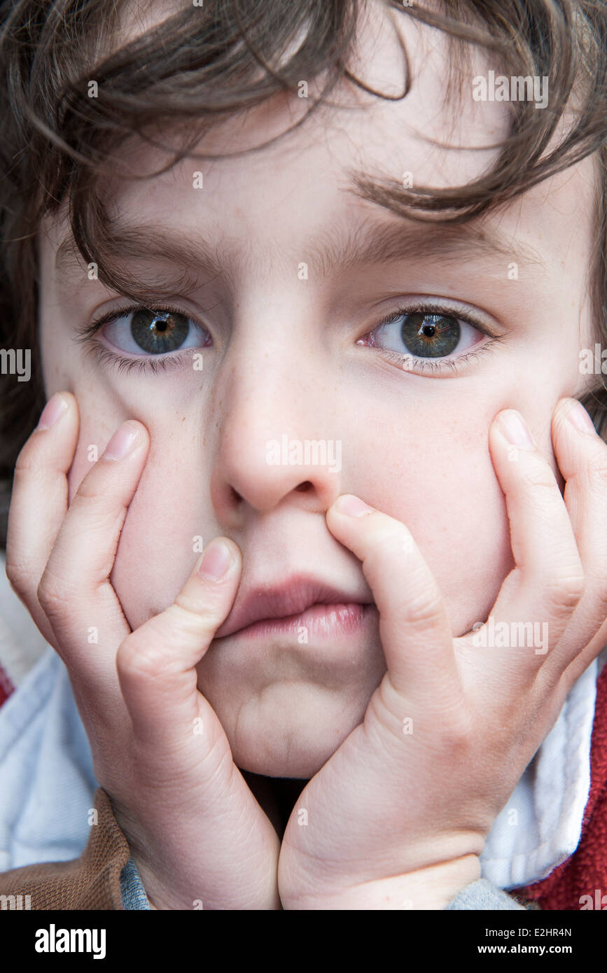 Boy resting chin in hands, bored expression on face Stock Photo