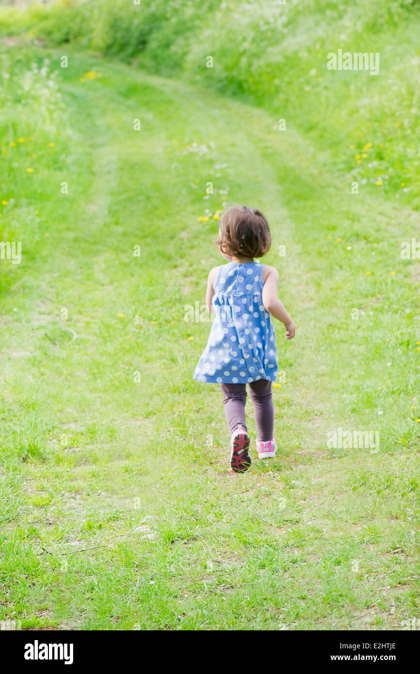 Little girl running on path through countryside, rear view Stock Photo